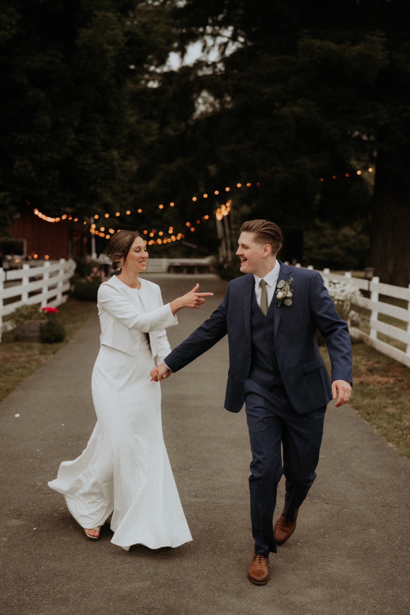 Bride and groom walking together under evening string lights