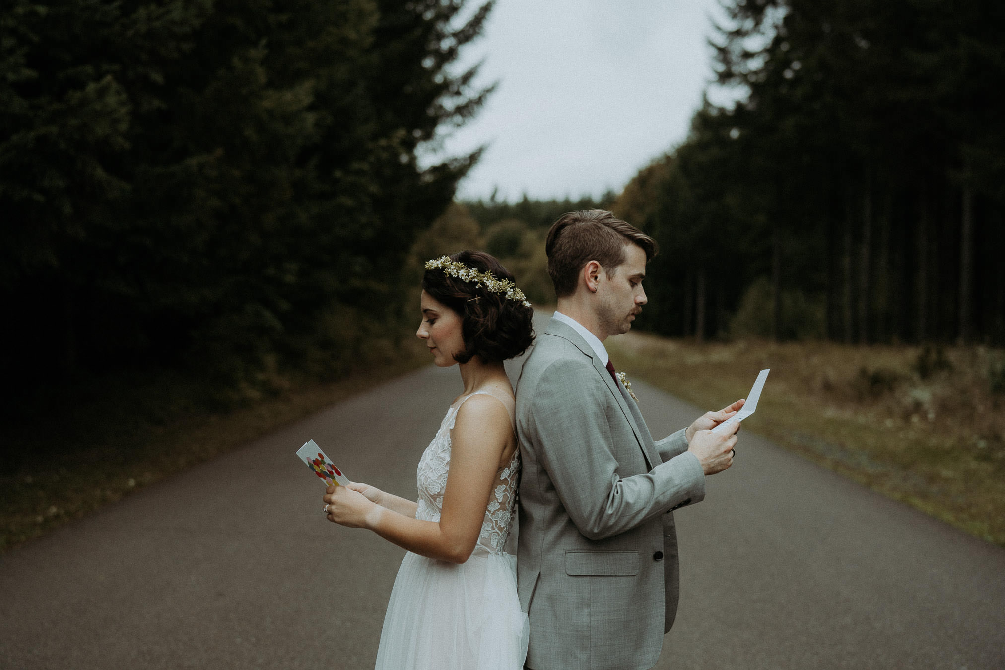 Newlyweds walking through an Oregon forest with drinks in hand
