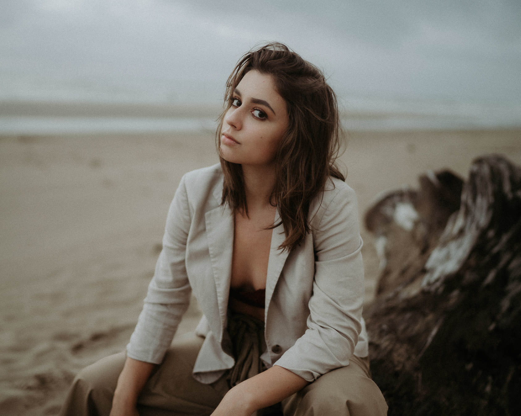 A woman in a light jacket looking toward the camera on an Oregon beach