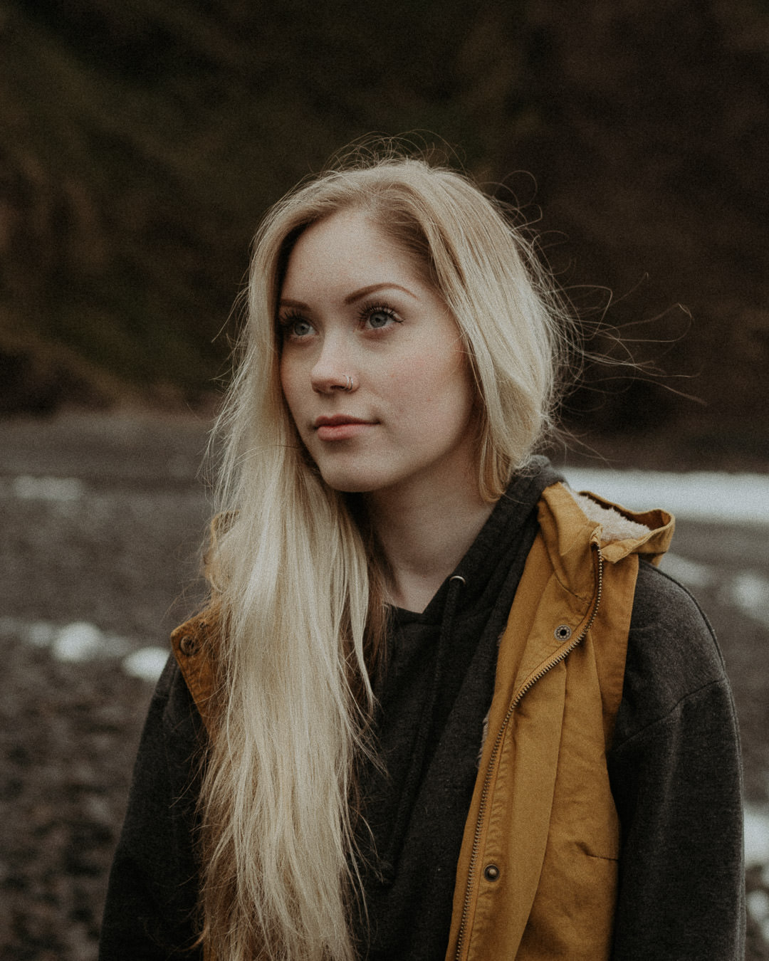 A woman in an outdoor jacket with a gray hood beside a rocky Oregon beach